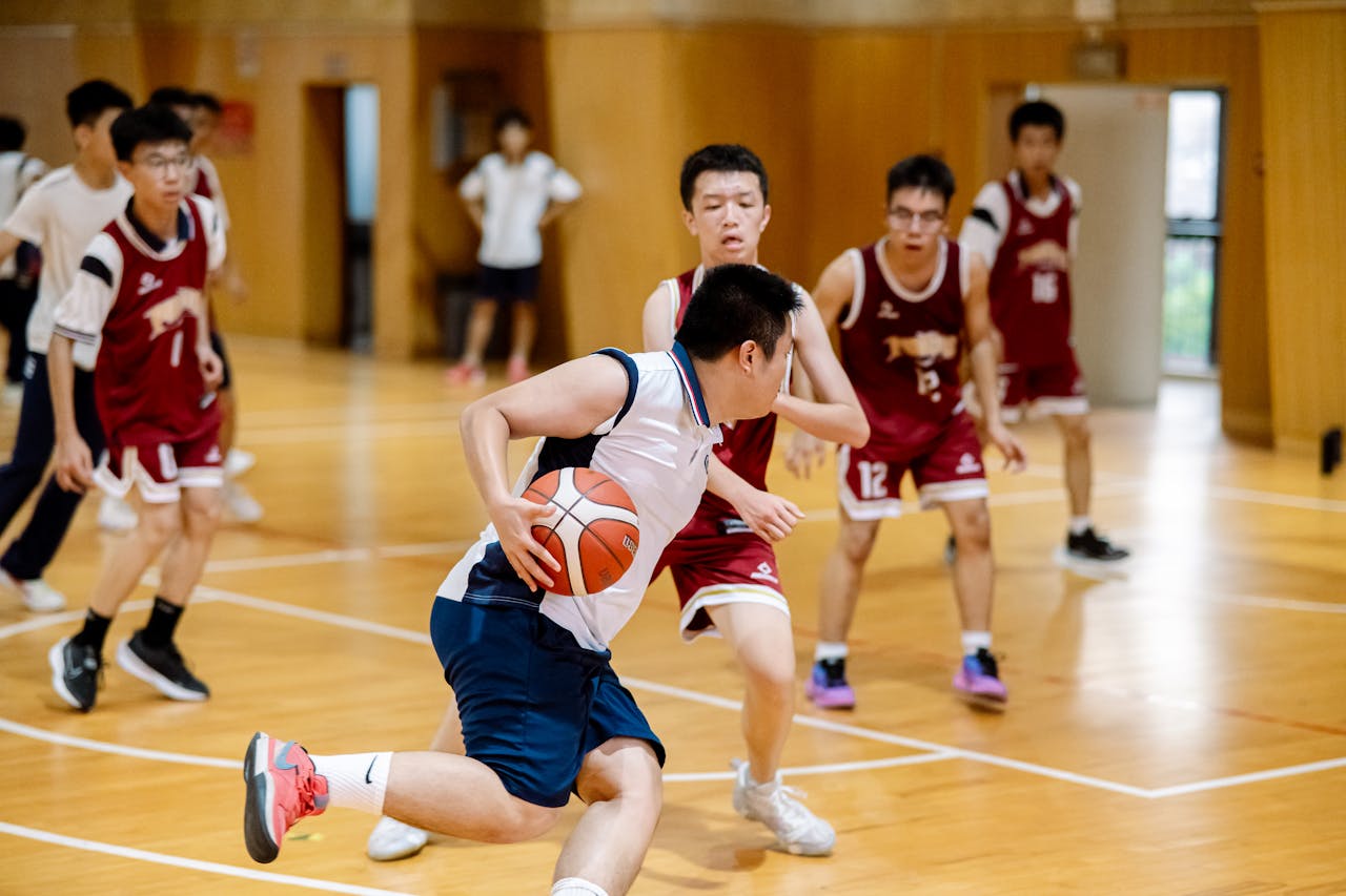 Teenagers playing basketball in an indoor court, showcasing competitive sportsmanship.
